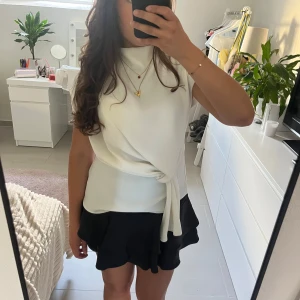 Vit festtopp - Jättesnygg vit festtopp från Zara. Den har en flowig design med en knut vid sidan. Jättebra när du vill vara lite extra fin. Endast använd några enstaka gånger. Passar xs-m eftersom den är åt det lösare hållet.