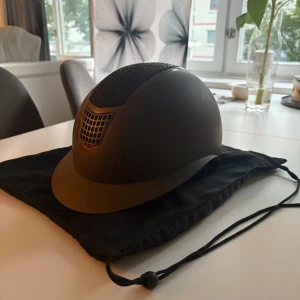 Ridhjälm - Säljer min ridhjälm från CRW köpt på hööks. Endast använd 2 gånger (ingen avramling) då jag slutat med ridning och hästarna. Hjälmen är i bra skicl. Brun med solskärm och svart glitter. Pris går att diskutera vill bara bli av med den