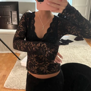 Spets topp - Supersnygg svart blus i transparent spets från Gina Tricot. Blusen har lång ärm, v-ringad hals och blommigt spetsmönster. Säljes i storlek S! Den har lite defekter men inget som man tänder på. 