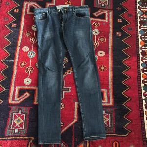 Jacob Cohen mörkblå jeans - Snygga mörkblå jeans från Jacob Cohen med klassisk femficksdesign och gulddetaljer på fickorna. Jeansen har raka ben och subtila slitningar för en cool look. Tillverkade i mjukt denim med jacronpatch och broderad logga. Storleken är 32 Skriv om ni har några frågor! 