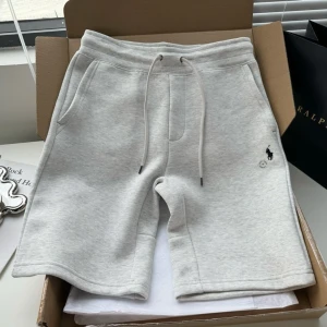 Grå shorts från Ralph Lauren - Snygga ljusgrå shorts från Ralph Lauren i mjuk bomull med normal passform. De har elastisk midja med snörning, två sidofickor och en bakficka. Klassisk broderad logga på ena benet. Perfekta för chill dagar eller när du vill vara bekväm men ändå stilren.