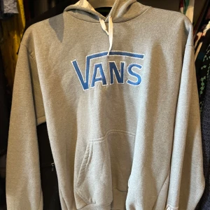 Grå hoodie från Vans - Snygg grå hoodie från Vans med stor blå logga framtill. 