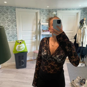 Svart blommig spetsblus med v-ringning - Säljer min superfina ”fest topp” ifrån Gina Tricot, inköpt våren 2025. Det är en genomskinlig tröja med ett fina blommig mönster i svart, super skönt att ha på sig och perfekt till en utekväll! Då den inte sitter så tight på mig så säljer jag den till någon som klär i den bättre! Tröjan är använda fåtal gånger och ser ut att vara helt ny. Den är i storlek M men skulle säga den passar L också. Nypris ca 300kr, mitt pris 100kr 