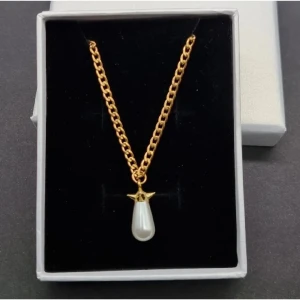 Guldhalsband med pärlhänge - Stilrent halsband med tjock guldfärgad kedja och ett droppformat vitt pärlhänge. Hänget har en cool stjärndetalj i guld upptill som ger extra edge. Perfekt för dig som gillar att sticka ut med enkla men snygga smycken.