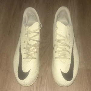 Nike Mercurial vita fotbollsskor - Gula nike mercurial clubs som är nästan helt ny. Har lite gummi från konstgräs fast på toppen av båda skor men mest på den högra