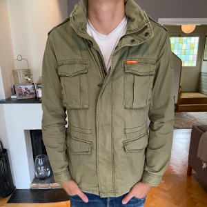 Superdry Field Jacket - Säljer nu denna sjukt snygga Field Jacket från Superdry! Storleken är L och modellen på bild är 188. Nypris runt 1400kr. Hör aver vid funderingar!