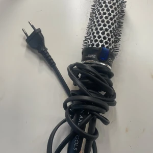 Rundborste med värme från Björn Axén 30 mm - Elektrisk rundborste med värmefunktion och jon-teknologi från Björn Axén. Borsten har svarta och silverfärgade borst samt ett svart handtag med blå detaljer. Perfekt för att styla och forma håret med volym. Inte använd alls mycket. 