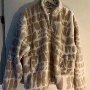 Beige och vit teddyjacka från LXA - Mysig teddyjacka från LXA i beige och vitt med unikt mönster. Jackan har dragkedja framtill, hög krage och två fickor. Helt oanvänd och går ej att få tag på längre🤎🤍