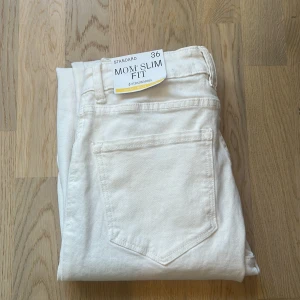 Vita mom jeans med slim fit från Stradivarius - Säljer ett par vita mom jeans från Stradivarius i slim fit-modell.  Strl 36, aldrig använda. 