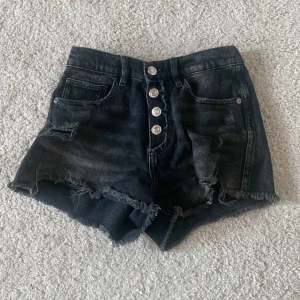 Svarta jeansshorts med knappar från Zara - Svarta jeansshorts från Zara med fyra silverfärgade knappar framtill. Storlek 11-12år köparen står för frakten🤗