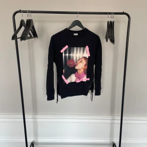 Svart sweatshirt från Kenzo med tryck - Cool svart sweatshirt från Kenzo med stort färgglatt tryck framtill och rosa detaljer. Tröjan har långa ärmar och dragkedjor i sidorna för extra stil. Perfekt statement-plagg för dig som vill sticka ut. Köpt på NK för ca. 2000kr för några år sedan. 