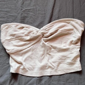 Beige ribbad tubtopp - Tubtopp med twistad detalj framtill. Finns sån delatj me silikon som håller den uppe