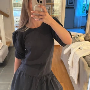 Svart klänning med puffärmar - Säljer en svart klänning med rund halsringning och puffiga kortärmar. Klänningen har en lös passform och volang nedtill, vilket ger en söt och trendig look. Perfekt för dig som gillar stilrena och enkla plagg med en twist.