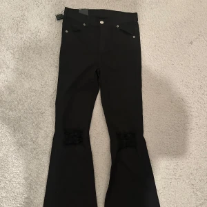 Svarta bootcut jeans från Dr Denim - Svarta jeans från Dr Denim, modell Macy, med bootcut och super skinny fit upptill. Aldrig använda. Byxorna har klassiska fickor fram och bak samt diskreta slitningar vid knäna. Perfekta för dig som gillar en modern och stilren look.