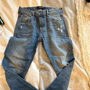 Blå jeansbyxor Replay Roxel - Säljer ett par klassiska blå jeansbyxor från Replay, modell Roxel. Byxorna har fem fickor, bälteshällor och slitna detaljer framtill för en trendig look. Perfekta till vardags och lätta att matcha med olika stilar.