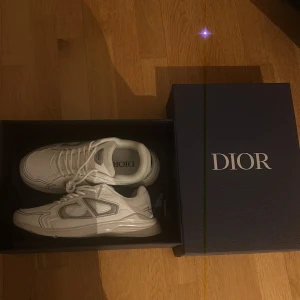 Vita sneakers från Dior (b30) - Säljer ett par vita b30 Dior. De är helt nya och har aldrig använt de eftersom de passar inte mig. De är i super bra skick och jätte stiliga. Hör av er för mer information 🤝 pris kan diskuteras