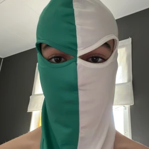 Grön och vit balaclava - Säljer en tvåfärgad balaclava i grönt och vitt. Huvudbonaden täcker hela ansiktet förutom ögonen och är sydd i ett mjukt, stretchigt material. Perfekt för kalla dagar eller som statement-piece.