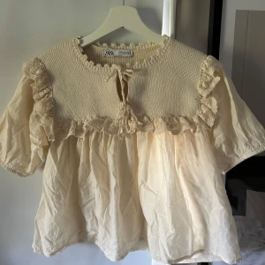 Blus från Zara  - Säljer en super söt  blus i en krämvit färg med knyte i kragen, spets detaljer och puffärm💋