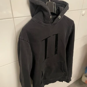 Svart hoodie från Les Deux - Säljer en svart hoodie från Les Deux med stor logga framtill. Tröjan har huva  och en stor magficka. Perfekt för dig som gillar stilrena och bekväma plagg. Storlek M. Hör av dig vid funderingar.