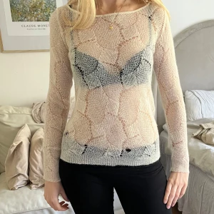 Beige transparent stickad tröja - Säljer en beige transparent stickad tröja med lång ärm och rund halsringning. Tröjan har ett unikt mönster och är tunn i materialet. 