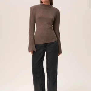 Brun stickad tröja med knytdetalj bak Adoore - Säljer en brun stickad tröja med lång ärm och hög hals. Tröjan har en snygg knytdetalj i ryggen som ger en unik look. Perfekt till både jeans och kjol. Stilren och enkel att matcha.