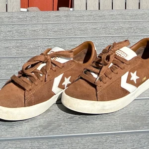Bruna Converse sneakers i mocka - Säljer ett par bruna Converse Con sneakers i mocka med vit sula och vita detaljer på sidan. Skorna har snörning och klassisk Converse-logga. Delvis använda, skick enligt bildspelet. Vita snöraren tillkommer! 