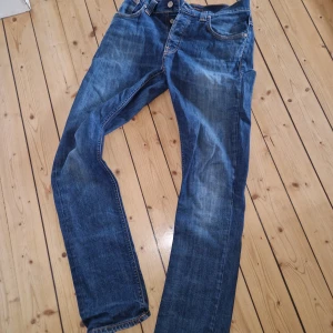 Nudie jeans Grim Tim - Ett par asfeta Grim Tim i mycket bra skick. Det finns en mycket liten defekt i skrevet som inte syns på bilden men skickar om det efterfrågas! Finns även en slitning jag har gjort själv på den högra fickan.                                                                        Storlek är 30/32 och bilder när jag har på mig på mig jeansen kan också skickas. De sitter lite mer relaxed än många andra slimjeans och passar dunder med t.ex margiela GAT. Kan gå ned i pris vid en snabb och smidig affär!