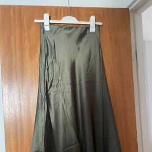 Olivgrön satinkjol - Säljer en olivgrön långkjol i satin. Den är tyvvär för liten för mig men annars jättefin! Den är ny med lappen kvar, ursprungligen från lager 157 och kostade 150kr när jag köpte den!