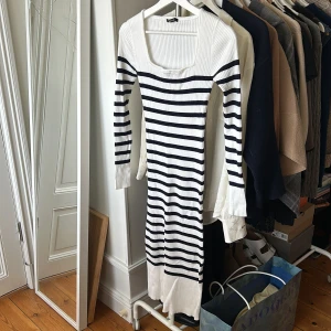 Gina Tricot randig långa klänning stickad  - Säljer en ribbad långärmad klänning från GinaTricot med vita och marinblå horisontella ränder. Klänningen har fyrkantig ringning och är figurnära med stretchigt material. Perfekt för dig som gillar en klassisk och stilren look.
