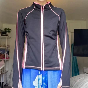 Träningströja / jacka - Sportig svart jacka/tröja med rosa detaljer och dragkedja. Jackan har långa ärmar med tumhål, rosa meshpaneler på sidorna för luft! Och praktiska fickor med dragkedja. Perfekt för träning eller utomhusaktiviteter när det är lite kallare och blåser😻Barnstorlek men kan passa XXS om du har kortare armar än mig🫣