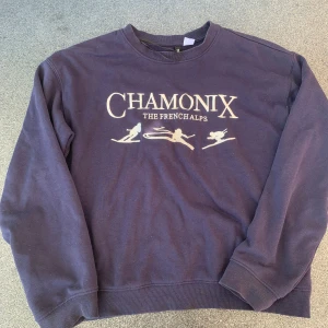 Mörkblå Chamonix sweatshirt - Säljer en mörkblå sweatshirt med tryck 'CHAMONIX THE FRENCH ALPS' och skidmotiv framtill. Tröjan har rund halsringning och långa ärmar. Perfekt för dig som gillar alpstilen och vill ha en chill vibe.
