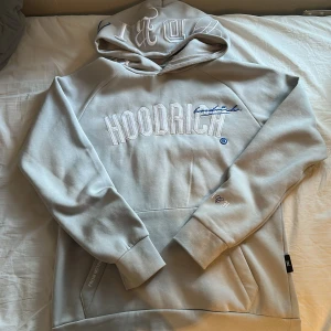 Beige hoodie från Hoodrich XS - Snygg beige hoodie från Hoodrich i storlek XS. Stor broderad logga framtill, tryck på ryggen och detaljer på huvan. Praktisk ficka med dragkedja och klassisk känguruficka. Mjuk bomullsblandning och relaxed fit, perfekt för chill dagar.