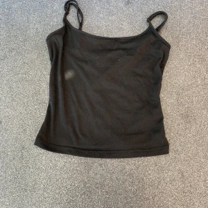 Svart enkel linnetopp - En stilren svart linnetopp med smala axelband och rak passform. Perfekt att matcha med jeans eller kjol för en clean look. Mjuk och skön känsla, passar till många olika outfits.