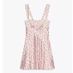 Blommig kortklänning med breda axelband - Supersöt kortklänning med blommigt mönster i rosa och lila toner på ljus botten. Klänningen har breda axelband och en lätt utställd kjol, perfekt för varma dagar. Snygg passform som känns både trendig och bekväm. Rosett där bak