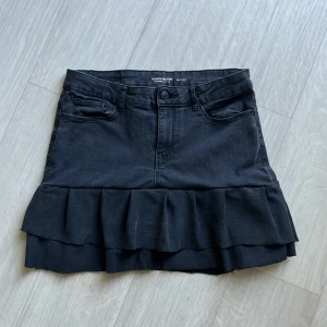 Mörkgrå low waist jeans volang kjol - Supersnygg svart jeans kjol från Vero Moda. Perfekt för dig som gillar en trendig och cool stil😎❤️Är M men sitter på som en S. Om ni hittar intresse så ede bara att meddela genast💗