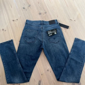 Blå Replay 573 jeans straight fit - Tvär feta jeans från Replay, modell 573 Clouds. Klassisk femficksdesign, raka ben och slim passform. Jeansen har en mörk tvätt och är tillverkade i mjukt denimtyg med Replay-läderpatch bak i midjan. Riktigt feta med en riktigt snygg färg som matchar till riktigt najs outfits!