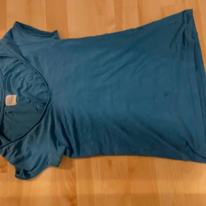 En enkel blå basic t-shirt - Enkel blå t-shirt med v-ringad hals och korta ärmar. Mjukt stretchigt material. Säljer för jag  hade inte så mycket användning av den.