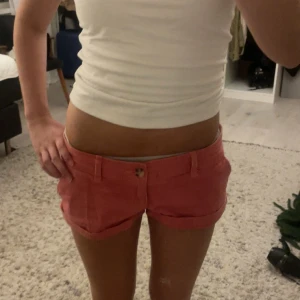 Rosa shorts från Abercrombie & Fitch - Snygga låga rosa shorts från Abercrombie & Fitch med stretch. Klassisk femficksmodell, uppvikta ben och knappstängning framtill. Perfekta för varma dagar och riktigt sköna tack vare stretchigt bomullsmaterial.