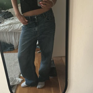 Blå wide jeans med rå kant - Säljer ett par blå jeans med breda ben och avklippt kant nertill från HM. Jeansen är egentligen högmidjade i storlek 40 men sitter lågmidjat och baggy på mig som är en storlek 36. Typ aldrig använda men säljer då de är för stora.