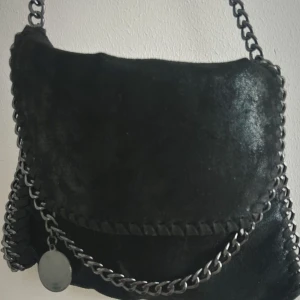 Svart axelväska med kedjedetaljer - Snygg svart axelväska i mocka!! Är i bra skick inga vidare defekter🫰🏽i får man plats med mobil, plånbok och en hårborste.🩷