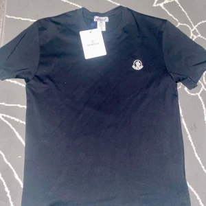Svart Moncler t-shirt i bomull - Jag säljer en mocler t shirt som har storlek 2XL men passar mer som XL o L, tröjan fraktas direkt efter köpet, vid frågor skrev direkt o jag svarar snabbt