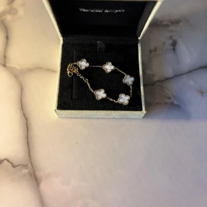 Van Cleef-smycke – Vitt - Elegant och tidlöst smycke med vit detalj. Ger en lyxig, ren känsla som passar perfekt till både ljusa och mörka outfits.