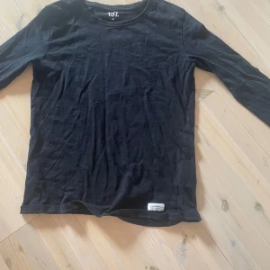 Svart långärmad tröja från 157 - En basic svart långärmad tröja från 157 i mjuk bomull. Enkel och stilren med rund halsringning, perfekt att matcha med jeans eller under en hoodie. Skön passform och passar till alla säsonger. Den är lite kort i ärmarna och därför säljer jag💕 