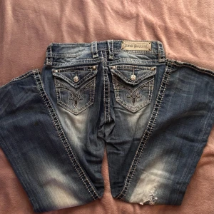 Low waist Rock Revival blå jeans - Coola blå jeans från Rock Revival med slitningar och broderade bakfickor med silverfärgade detaljer🪽❤️