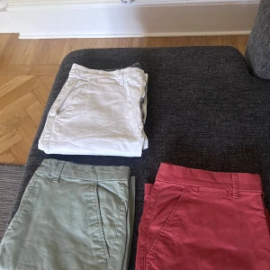 Tre par klassiska shorts i olika färger - Säljer tre par stilrena shorts i vitt, ljusgrönt och orange . Alla har klassisk LARGE passform med fickor i sidorna och hällor för bälte. Perfekta för varma dagar och enkla att matcha med t-shirt eller skjorta. Materialet känns som bomull och är mjukt mot huden.