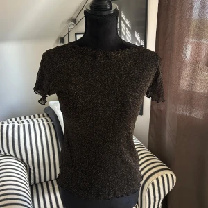 Glittrig svart sheer topp med volangkant - Snygg svart sheer topp med glittriga inslag och korta ärmar i storlek M men funkar även till S💕