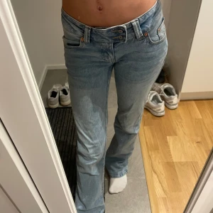 Ljusblå bootcut jeans med broderad ficka - Säljer ett par ljusblå jeans med bootcut passform och snygg broderad detalj på bakfickan. Jeansen har låg midja, klassiska fem fickor och är tillverkade i mjukt denim. Perfekta för dig som gillar en avslappnad men ändå trendig look.