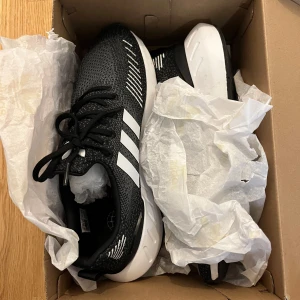 Adidas skor - Säljer mina snygga svarta Adidas sneakers med klassiska vita ränder. Skorna är helt nya och säljer pga de är för stora. Perfekta för dig som gillar sköna och snygga skor som passar till vardags och sport. Orginal priset är 1 145kr!                        OBS! Köparen står för frakten!