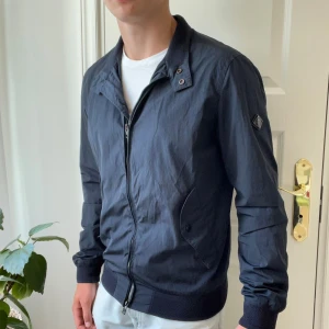 J.lindberg jacka  - Skön vindjacka från j.lindberg, defekter: minimal defekt på dragkedjan, då den har tappat lite färg. Modellen är 180,75 kg och bär M. Kom med frågor✌️