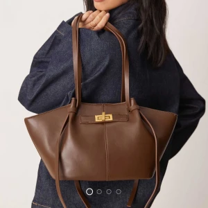 Brun axelväska i skinn med gulddetalj - Skit snygg väska från Gina tricot, slutsåld på hemsidan! Ingen typ av defekt men kommer bara inte till användningn! Den är i den lilla storleken❤️